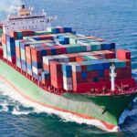 Hormuz Ambush Sparks Global Panic A large cargo ship loaded with colorful containers sailing on the ocean