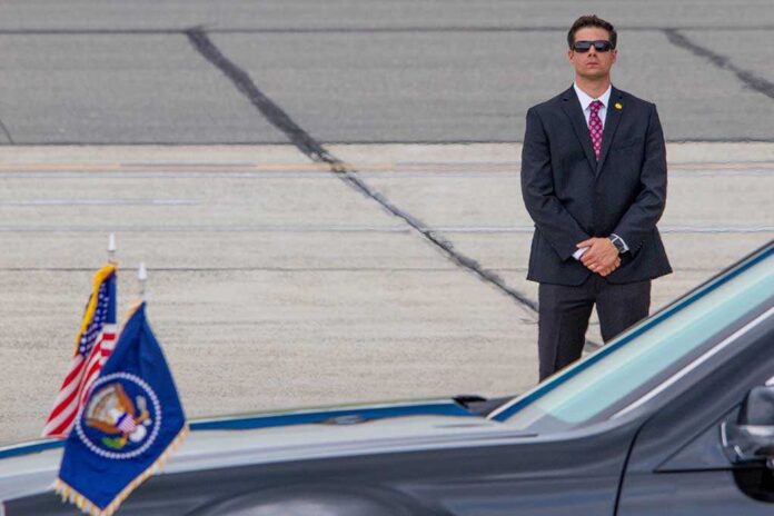 A security officer in a suit stands guard near a presidential vehicle at an airport