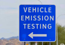 Blue sign for vehicle emission testing direction.