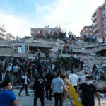 Cameras Roll As Mega Quake Hits People at a collapsed building after an earthquake.