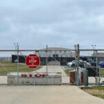 Base Breach Sparks Fentanyl Panic Chain-link fence with Restricted Area Stop No Photography sign.