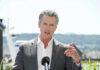 FBI Knocks: Newsom’s Inner Circle Scrutinized Man speaking with microphone outdoors.