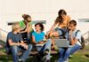 Group of students sitting on a bench outdoors, engaged in study and discussion