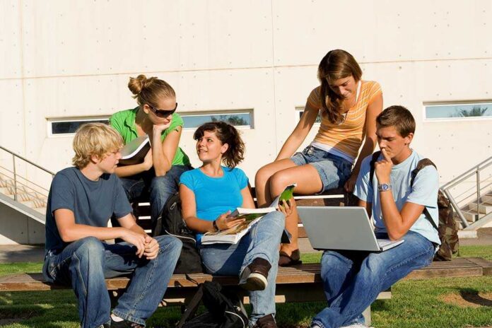 Group,Of,Students Group of students sitting on a bench outdoors, engaged in study and discussion