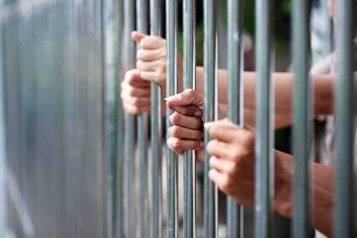 Hands gripping metal prison bars
