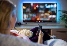 Fox Grabs Roku — TV Power Flip Person sitting on a couch watching a movie on a TV with popcorn in hand