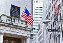 Facade of the New York Stock Exchange with an American flag and Wall Street sign