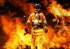 Uncontained Monster Fire Torches Ski Haven Firefighter standing in front of a large fire, equipped with tools