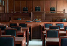 Grok Scandal Deepens — Who’s Really Liable? Empty courtroom with wooden furnishings and judges bench.