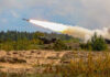 Deterrence Theater Backfires — What’s The Plan? Military tank firing a missile in forest area.