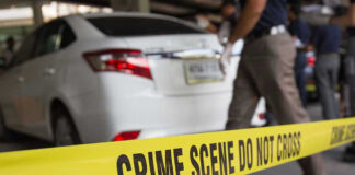Crime scene tape blocking off white sedan.