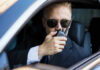 Trump vs. CIA: Who Bent The Truth? Man in suit using walkie-talkie in car.
