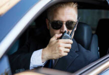 Trump vs. CIA: Who Bent The Truth? Man in suit using walkie-talkie in car.
