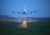 Name Bombshell: First Airport Honors Sitting President An airplane approaching the runway at night with landing lights illuminated