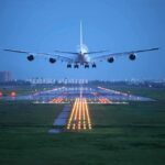 Name Bombshell: First Airport Honors Sitting President An airplane approaching the runway at night with landing lights illuminated