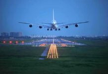 An airplane approaching the runway at night with landing lights illuminated