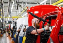 White-Collar Purge At BMW Worker assembles red vehicle on factory line