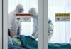 Outbreak Escalates, First Vaccine Given Healthcare workers in hazmat suits treat a patient in a quarantine room