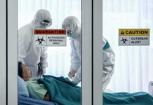 Healthcare workers in hazmat suits treat a patient in a quarantine room