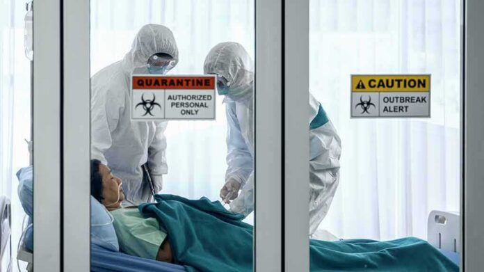 Healthcare workers in hazmat suits treat a patient in a quarantine room