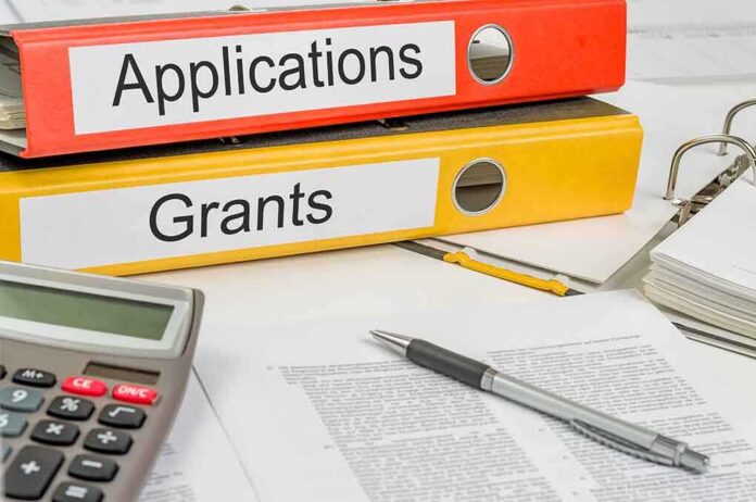 shutterstock_171944867 Two binders labeled Applications and Grants on a desk with a calculator and papers