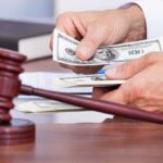 Currency Bombshell: Trump Name Lands On Bills A person counting cash in a courtroom setting with a gavel in the foreground