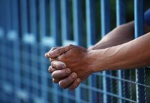 Eight-Car Carnage, Judge Goes Light Close-up of clasped hands resting on a blue fence
