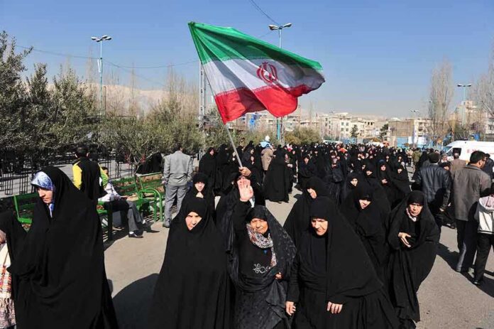 shutterstock_230251486 Group of women in black attire marching with an Iranian flag