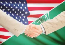 Nuclear Guardrails Dropped — What Did Trump Trade? Handshake between two people over U.S. and Saudi flags