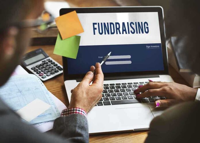 shutterstock_483164662-2- Two individuals discussing fundraising on a laptop with a sign-in screen