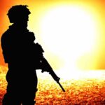 silhouette of an armed soldier against a bright fiery background