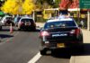 School Threat Suspect Walks — Days Before Class Starts Police cars with lights on near school buses on a city street