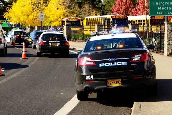 Roseburg,,Or,-,October,16:,Police,Cars,And,School,Buses Police cars with lights on near school buses on a city street