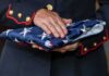 Routine Test, Dead Recruit — No Answers Uniformed person holding a folded American flag
