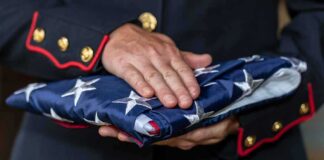Uniformed person holding a folded American flag