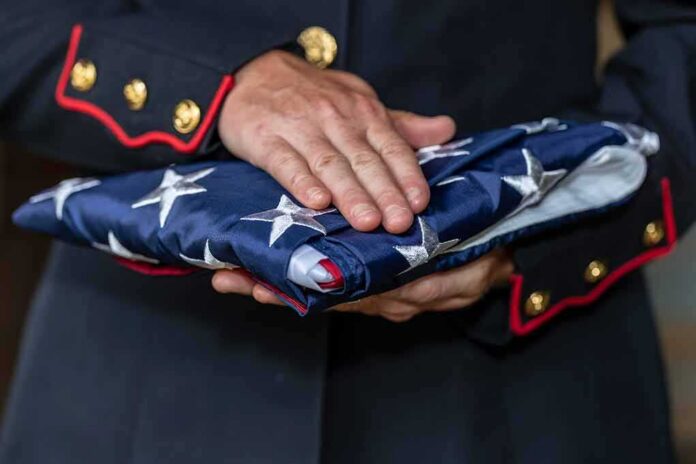 shutterstock_1177582333 Uniformed person holding a folded American flag