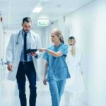 Doctors walking in a hospital corridor reviewing a tablet