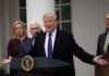 man speaking at podium with officials standing behind