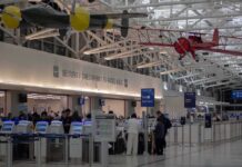 Airport Fight Erupts Over $300K Bathroom Add-On airport security checkpoint with passengers and hanging vintage airplanes