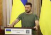 Zelensky Serbia Trip SHRINKS to Trade Huddle Man at a podium with Ukrainian flags