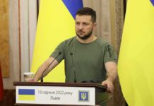 Zelensky Serbia Trip SHRINKS to Trade Huddle Man at a podium with Ukrainian flags