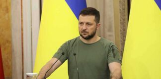 Man at a podium with Ukrainian flags