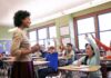 Teacher engaging with students raising hands in a classroom