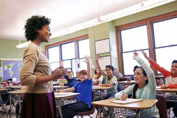 Teacher engaging with students raising hands in a classroom
