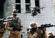 Quadcopter drone flying above soldiers in camouflage