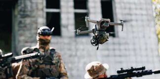 Quadcopter drone flying above soldiers in camouflage