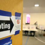 Voter Vouching Sparks Firestorm Voting sign on door leading to polling place