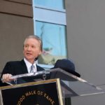 Bill Maher’s Burrito Math Ignites Backlash A man in formal attire speaking at a podium during a Hollywood Walk of Fame ceremony