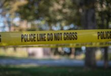 Priest Killed Inside Sacred Grounds yellow police tape cordoning off an outdoor area