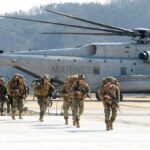 12-Year War Chapter Closes – Now What? Soldiers disembark and walk past a large military helicopter